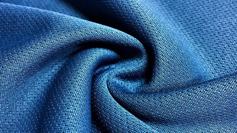 Close-up of blue textured fabric with intricate swirl pattern, highlighting the benefits of Coolmax.