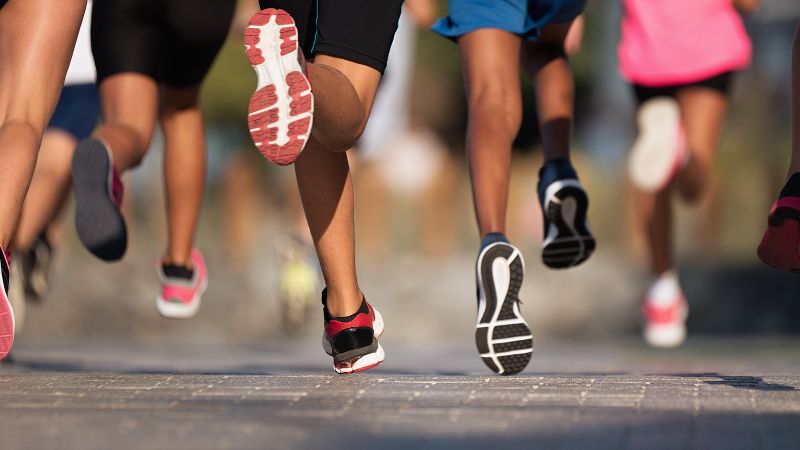 Grupo de corredores en un camino pavimentado, concentrándose en sus pies con zapatillas deportivas y calcetines acolchados Sinoknit.