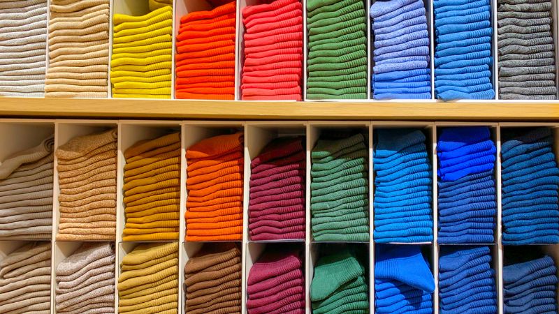 Neatly stacked colorful sweaters on shelves showcase the year-round comfort of moisture-wicking fabrics.