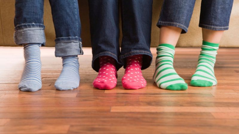 Trois paires de chaussettes à rayures et à pois avec des logos Sinoknit uniques sont présentées sur un plancher en bois.