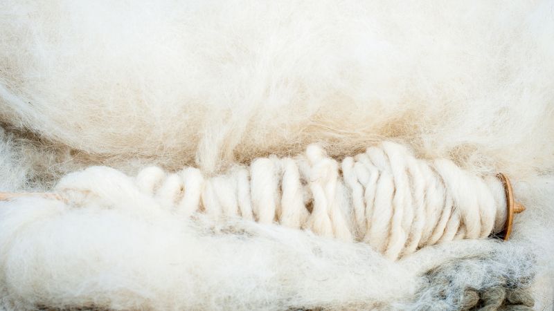 Soft natural wool yarn on a wooden spool, ideal for high-quality knitting and sustainable home textiles. Pure, eco-friendly fiber perfect for cozy blankets, garments, and craft projects.