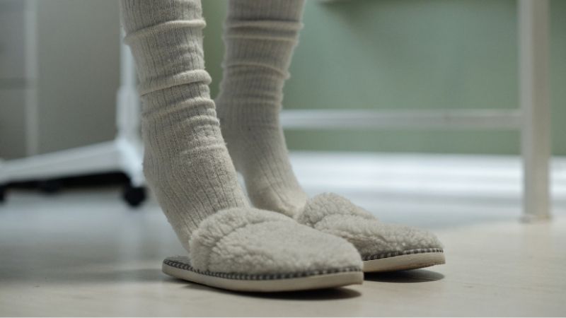 1. Cozy indoor slippers with fleece lining and soft socks on a light wooden floor for comfort and warmth.