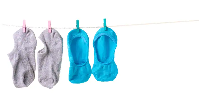 Socks hanging on a clothesline, including gray ankle socks and bright blue no-show socks, ideal for pairing with shorts for a casual, stylish summer look.