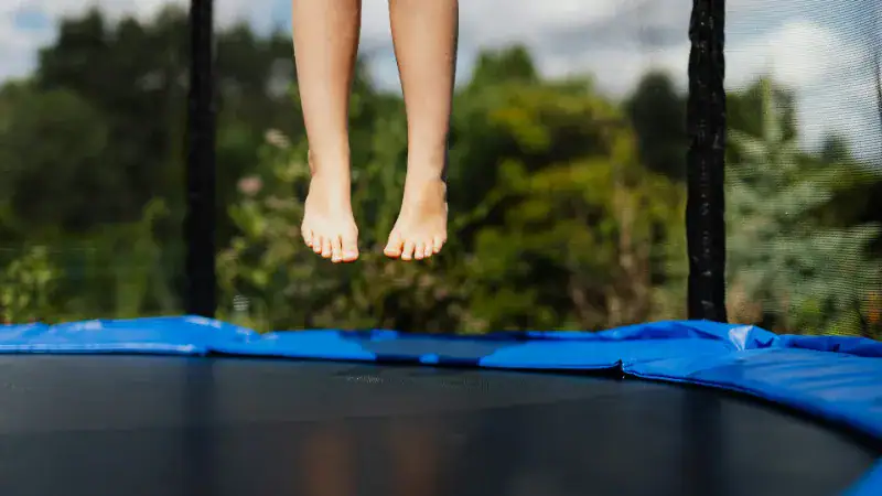 Close-up of bare feet and socks jumping on a trampoline, highlighting comfort and safety options for trampoline use.