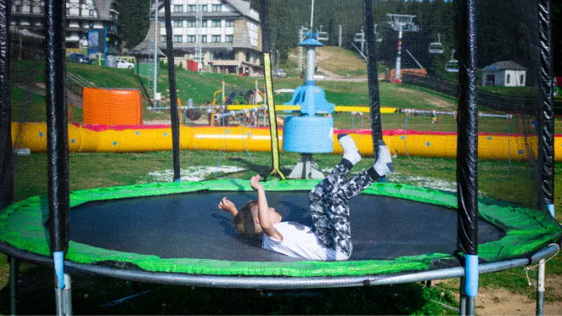 Child jumping on a trampoline wearing socks, with another barefoot, highlighting the differences for safety and comfort.