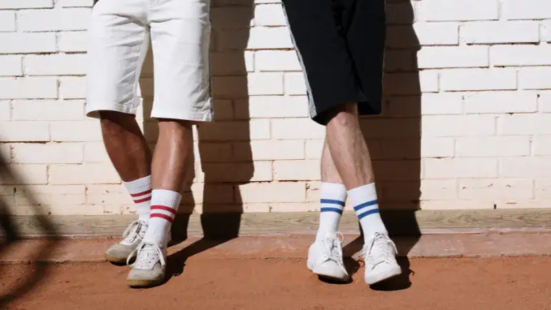 Men's casual striped socks paired with shorts and sneakers.