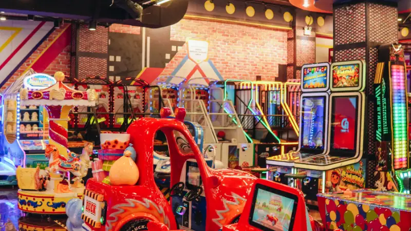 A vibrant arcade scene featuring a red toy car and various electronic gaming machines, creating an engaging and lively atmosphere perfect for entertainment and fun.